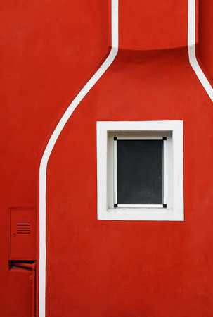 Detail of a red facade with white lines and a small window の写真素材
