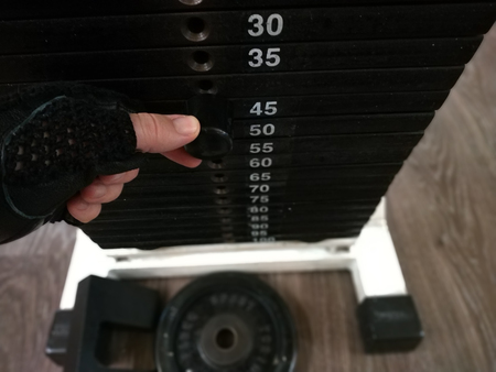 Choose the weight at the gym. To carry out the exercise with weights, the first thing to do is to fix the workload. The metal pin is threaded at the selected weight.の写真素材