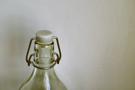 A transparent glass bottle on a neutral white background. Full of water, closing mechanism with gasket and cap.の写真素材