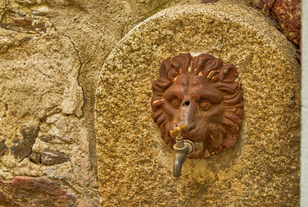 Mergozzo, Piedmont, Italy. March 2019. On the hill near the lake the village is one of the most beautiful villages in Italy. Detail of a fountain with the head of a lion.のeditorial素材