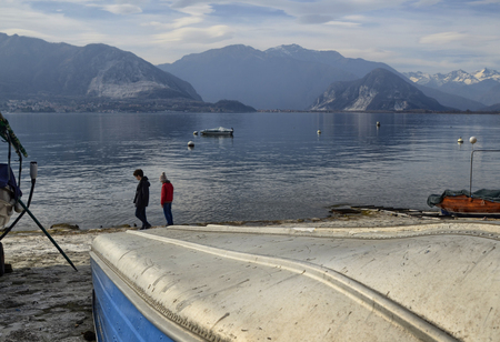 Verbania, Piedmont, Italy. March 2019. The lakefront offers a view of an idyllic landscape. Moored boats, small islands with luxuriant nature. Tourists stroll along the streetlights.のeditorial素材