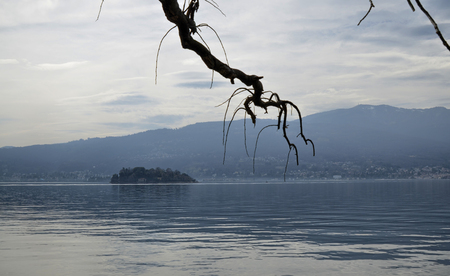 Verbania, Piedmont, Italy. March 2019. The lakefront offers a view of an idyllic landscape. Moored boats, small islands with luxuriant nature. Tourists stroll along the streetlights.のeditorial素材