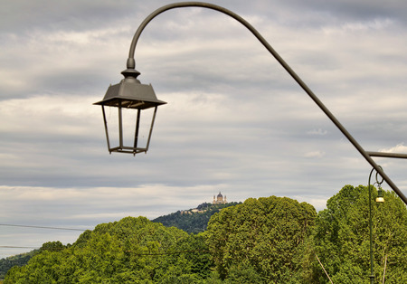 Turin, Piedmont, Italy. May 2019. The Basilica of Superga filmed by Piazza Vittorio. The green hills and a lamppost in the foreground are the settingのeditorial素材