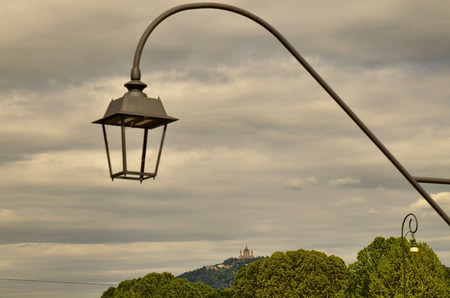 Turin, Piedmont, Italy. May 2019. The Basilica of Superga filmed by Piazza Vittorio. The green hills and a lamppost in the foreground are the settingのeditorial素材