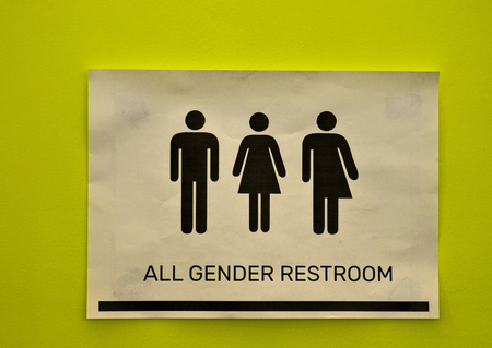 Toilet signage of all kinds next to a bathroom door in acid green with icons of the man, the woman, the transgender. Black icons on a white background.のeditorial素材