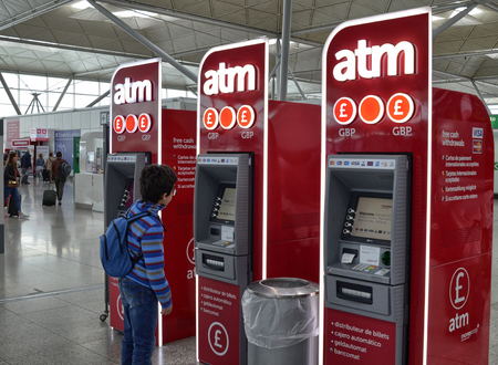 Stansted Airport - Stansted Express London, United Kingdom. June 14, 2018. A tourist child approaches the ATM terminals for cash dispensing.のeditorial素材