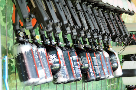 Paintball equipment. A rack packed with air guns. The gas-filled cylinders can be seen at the bottom. Above the tanks of paint bullets.の写真素材