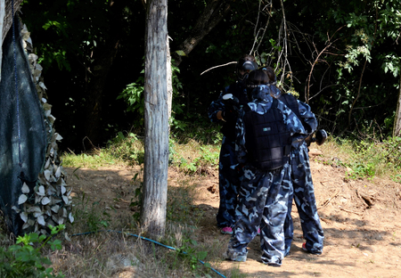 Battle at paintball. A small group of young players, fully equipped, are positioned to start the fight.の写真素材