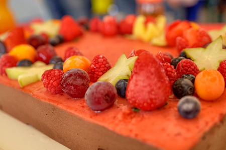 Appetizing fruit ice-cream cake decorated with strawberries, blueberries, cigliege, calamodino, kumquat, apple stars.の写真素材