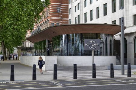 London, United Kingdom, June 2018. The Scotland yard, characterized by the brilliant rotating sign. On the opposite bank of the Thames the london eye.のeditorial素材