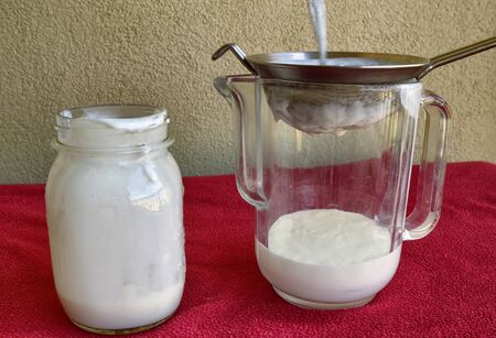 Pouring of Kefir, the glass jar is placed next to the net to pour the contents.の写真素材