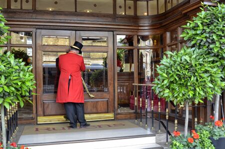 London, United Kingdom, June 2018. The typical uniform of the porters of London hotels, in this photo the Rubens hotel of red color.のeditorial素材