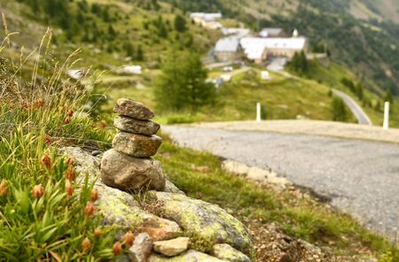 Stones stacked as a Zen memorial along a mountain road, a township in the background blurred and indistinguishable.の写真素材