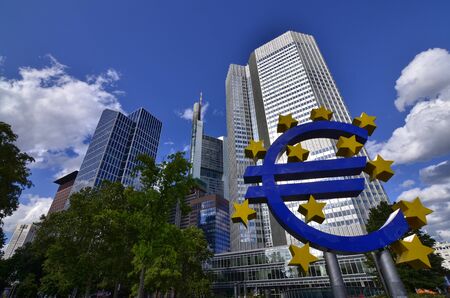 Frankfurt am Main, Germany, August 2019.  The Eurotower. White clouds on the blue sky. Highlighted on the right is the blue Euro symbol with yellow stars.