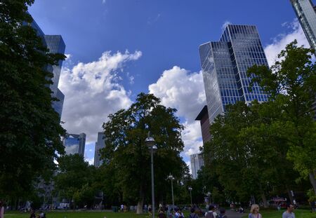 Frankfurt am Main, Germany, August 2019. The financial district is characterized by the greenery surrounding the numerous skyscrapers with mirrored facades. White clouds on the blue sky.のeditorial素材