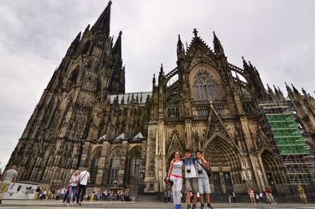 Cologne, Germany, August 2019. Side view of the cathedral, note the scaffolding for ongoing maintenance. At the base many tourists, some make a souvenir photo.のeditorial素材
