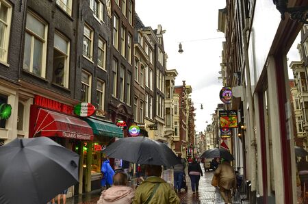 Amsterdam, Holland, August 2019. The alleys of the old town on a rainy day. The houses look a bit gloomy but the tourists are always present.のeditorial素材