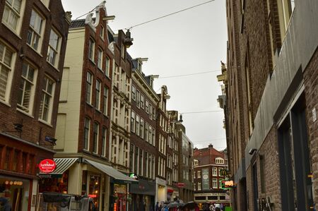 Amsterdam, Holland, August 2019. The alleys of the old town on a rainy day. The houses look a bit gloomy but the tourists are always present.のeditorial素材