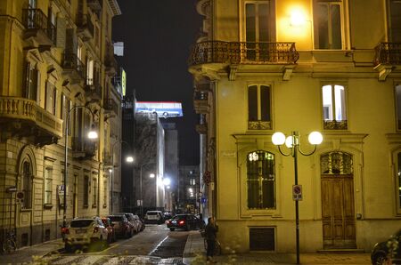 Turin, Piemonte, Italy. November 2019. A bus poised on the roof of a building. You can see the bus swinging slowly. It is an artistic installation in homage to the movie The Italian Job. Night shot.のeditorial素材