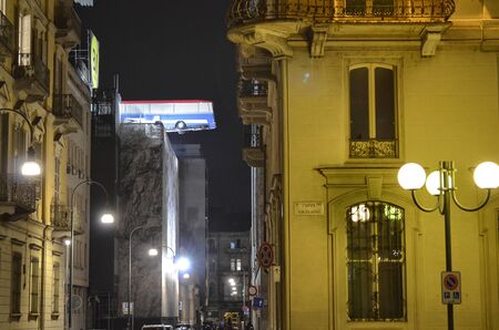 Turin, Piemonte, Italy. November 2019. A bus poised on the roof of a building. You can see the bus swinging slowly. It is an artistic installation in homage to the movie The Italian Job. Night shot.のeditorial素材