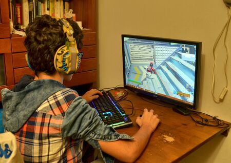 Turin, Piemonte, Italy. November 2019. A Caucasian boy is playing computer games. Use a gaming keyboard and mouse. Conceptual image.のeditorial素材