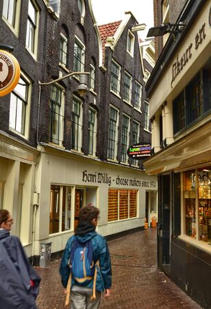 Amsterdam, Holland, August 2019. The alleys of the old town on a rainy day. The houses look a bit gloomy but the tourists are always present.のeditorial素材