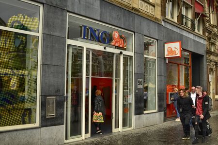 Amsterdam, Holland. August 2019. In the city it is easy to meet branches of the Dutch bank Ing Direct. A lady is entering. The orange lion logo is unmistakable. People walking.のeditorial素材