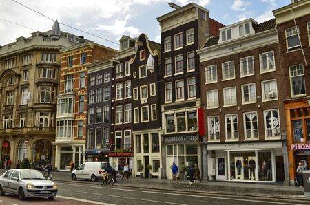 Amsterdam, Holland. August 2019. The streets of the historic center are characterized by the red asphalt strip reserved for bicycles. The typical houses overlook the street, sunny day.のeditorial素材