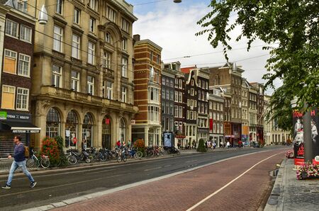 Amsterdam, Holland. August 2019. The streets of the historic center are characterized by the red asphalt strip reserved for bicycles. The typical houses overlook the street, sunny day.のeditorial素材