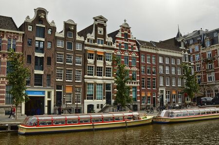 Amsterdam, Holland. August 2019. The large tourist boats that crowd the canals of the historic center: they move all day transporting large numbers of visiting tourists.のeditorial素材