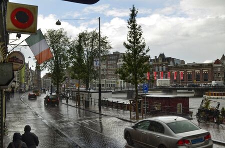 Amsterdam, Holland. August 2019. A rainy day: cars raise water splashes. In the distance the sky is clearing.のeditorial素材