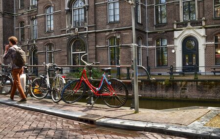 Amsterdam, Holland. August 2019. Bicycles are a symbol of the city, they are often parked on the railings of canals. A bike with a flaming red frame stands out along the road.のeditorial素材