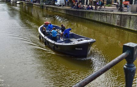 Amsterdam, Holland. August 2019. A boat along one of the canals of the historic center, passengers observe the surrounding landscape.のeditorial素材
