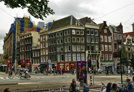Amsterdam, Holland. August 2019. A road junction in the center: the typical houses, cars, bikes, pedestrians, tram rails coexist.のeditorial素材