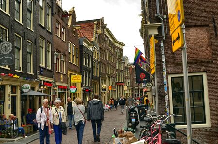 Amsterdam, Holland. August 2019. Particular view of the typical houses overlooking the street: a succession of shops and restaurants are presented at the sight of people on the street.のeditorial素材