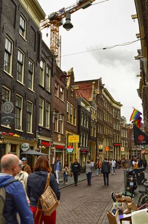 Amsterdam, Holland. August 2019. Particular view of the typical houses overlooking the street: a succession of shops and restaurants are presented at the sight of people on the street.のeditorial素材