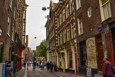 Amsterdam, Holland. August 2019. Particular view of the typical houses overlooking the street: a succession of shops and restaurants are presented at the sight of people on the street.のeditorial素材