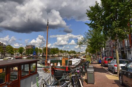 Amsterdam, Holland, August 2019. View of the Amstel River, outskirts of the city. A large moored boat is used as a houseboat. Sunny day with blue sky and white clouds.のeditorial素材