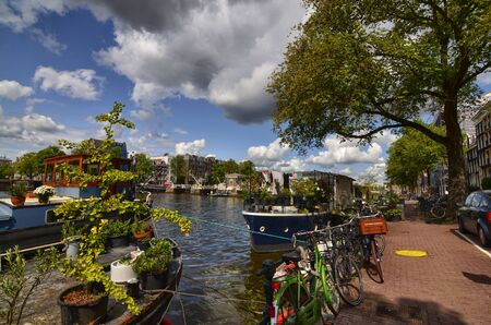 Amsterdam, Holland, August 2019. View of the Amstel River, outskirts of the city. A large moored boat is used as a houseboat. Sunny day with blue sky and white clouds.のeditorial素材