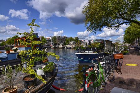 Amsterdam, Holland, August 2019. View of the Amstel River, outskirts of the city. A large moored boat is used as a houseboat. Sunny day with blue sky and white clouds.のeditorial素材