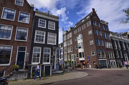 Amsterdam, Holland, August 2019. The typical houses of the historic center: made of brick and with white window frames. People walk in the street.のeditorial素材