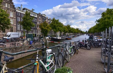 Amsterdam, Holland, August 2019. Parked bikes frame this view on one of the canals. Sunny day with white clouds and blue sky.のeditorial素材