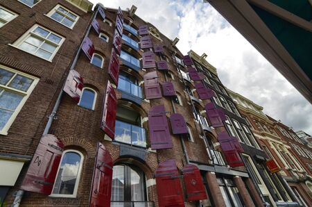 Amsterdam, Holland, August 2019. In the historic center, a typical building with characteristic red window doors.のeditorial素材