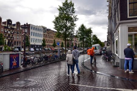 Amsterdam, Holland, August 2019. A worker from Thuisbezorgd, home delivery company for food and drink. It is easy to notice them: the showy the orange bag with the white writing.のeditorial素材