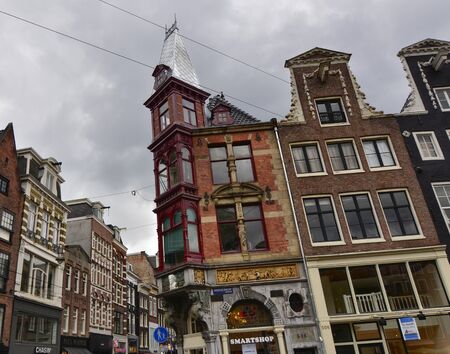 Amsterdam, Holland, August 2019. Rainy day in the old town. Among the typical little houses, a corner with a red bay window attracts the untidy standing out among the others.のeditorial素材