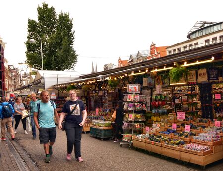 Amsterdam, Holland, August 2019. At the flower market, tourists walk along the sequence of exhibitor...