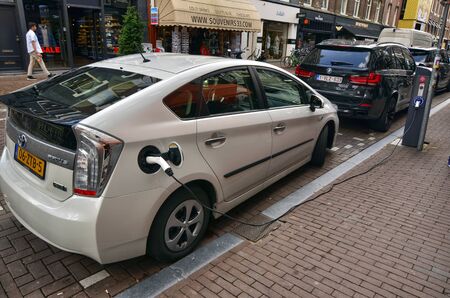 Amsterdam, Holland. August 2019. On the road a Toyota prius plug in is parked in recharge. The charging connector has been inserted into the appropriate socketのeditorial素材