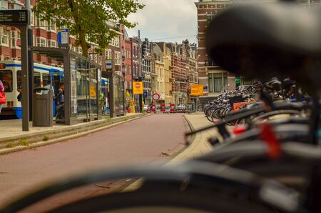 Amsterdam, Holland, August 2019.A particular point of view: from the blurred frame and saddle of a parked bike we see the cyclists passing on the cycle pathのeditorial素材