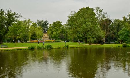 Amsterdam, Holland, August 2019. The Vondelpark: the large park in the heart of the city. On a rainy day, view of one of the lakes: people stroll with an umbrella enjoying the beauty of the place.のeditorial素材