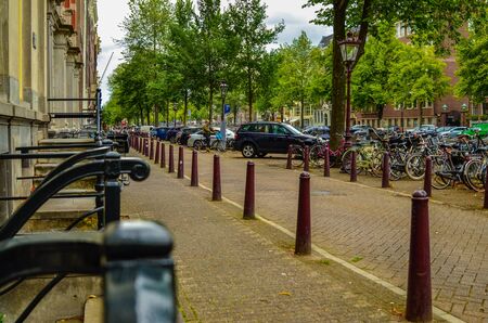 Amsterdam, Holland, August 2019. A street in the center: perspective on the dark green railings of the houses with street entrance and the brown stakes that mark the sidewalk.のeditorial素材